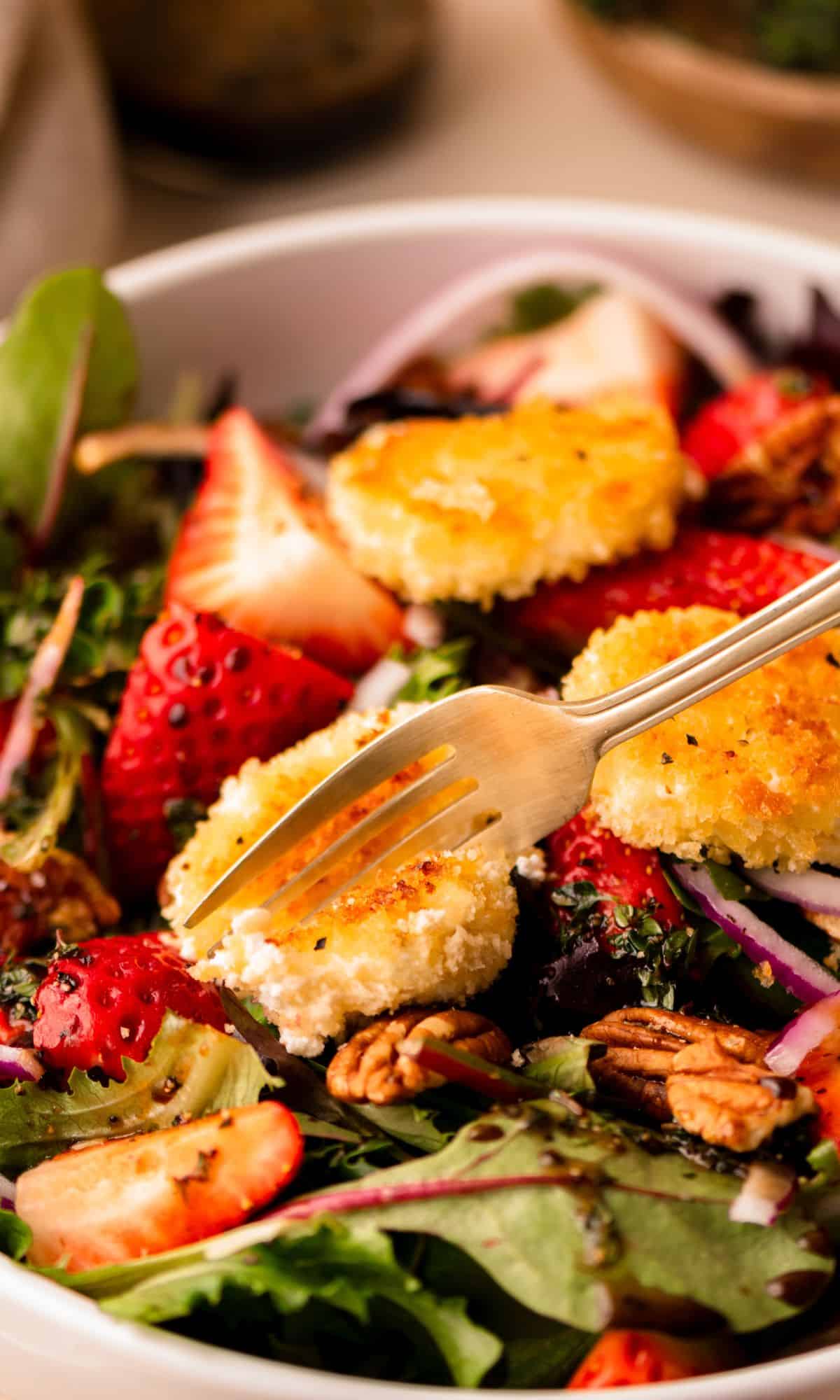 A fork cutting a goat cheese crouton in half.