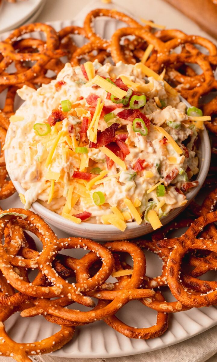 A bowl of pretzel dip surrounded by pretzels.