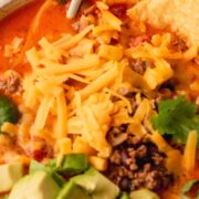 Taco soup in a white bowl topped with avocado, cheese and cilantro.