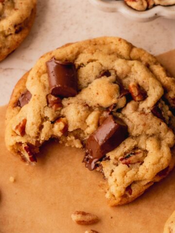 A chocolate chunk cookie with a bite taken out of it.