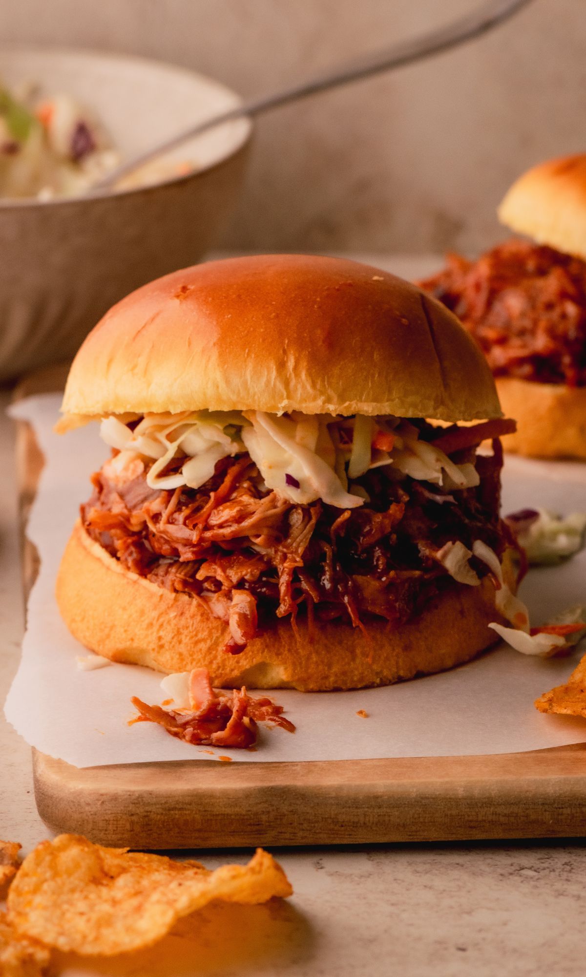 A pulled pork sandwich on a but and topped with coleslaw.