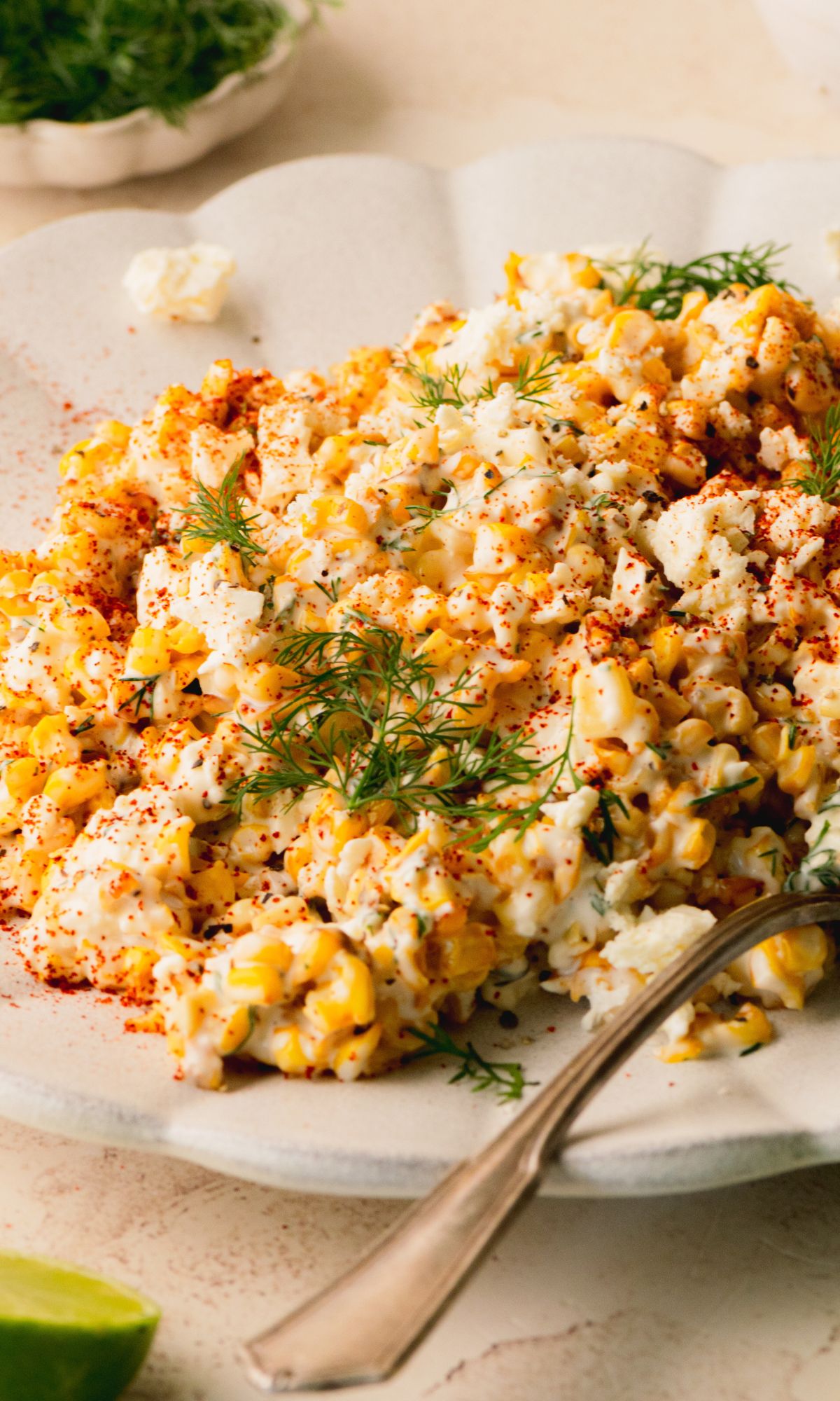 Corn salad on a white plate topped with fresh dill.