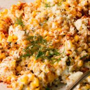 Corn salad on a white plate topped with fresh dill.