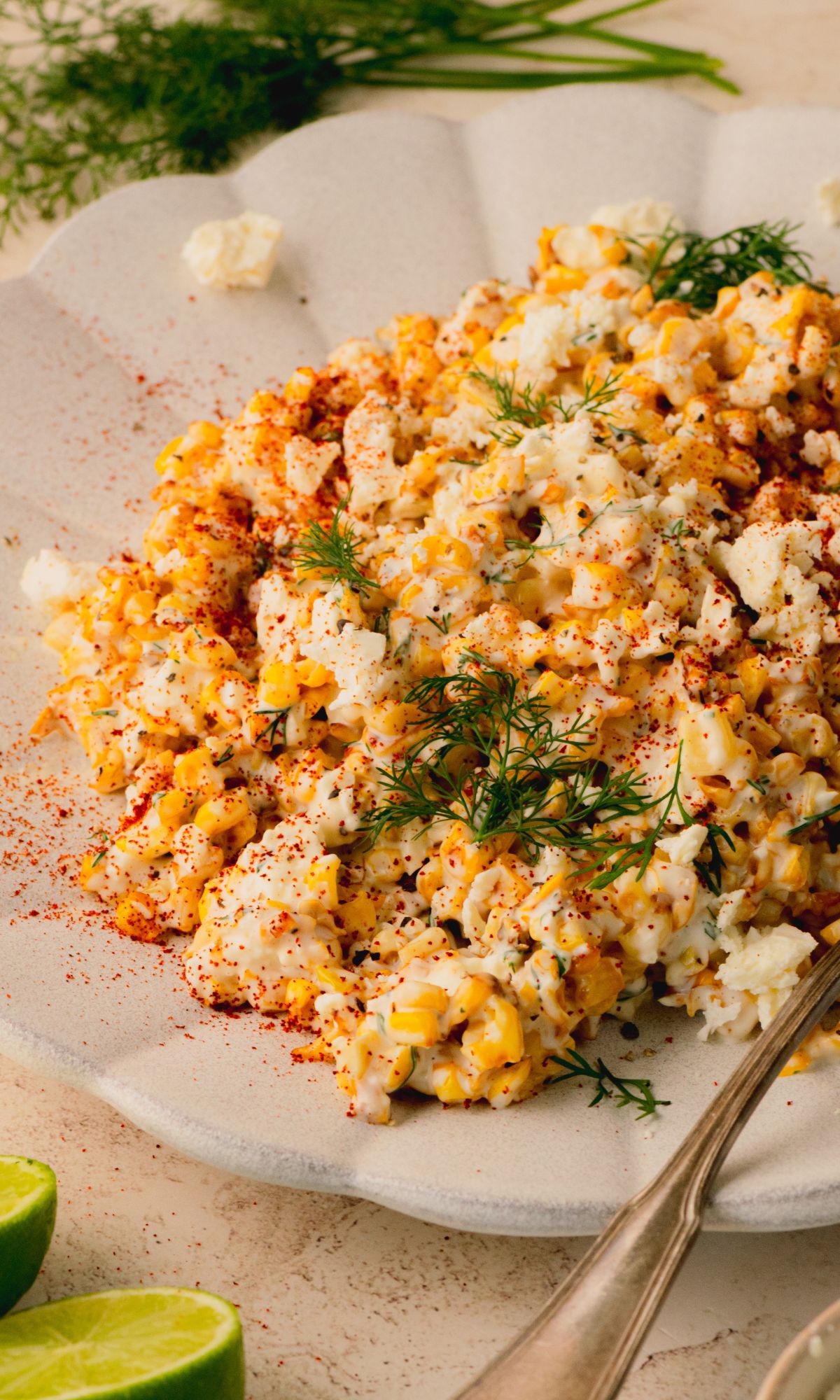 Corn salad on a white plate topped with fresh dill.