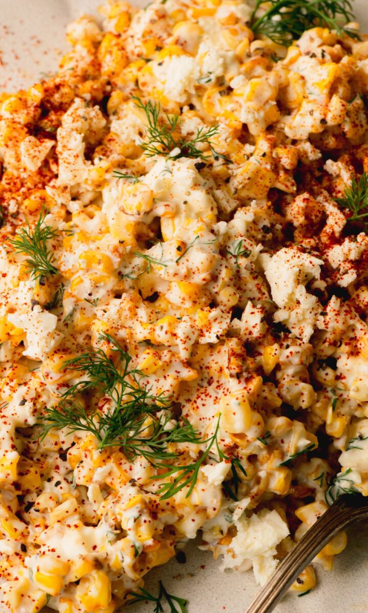 Corn salad on a white plate topped with fresh dill.
