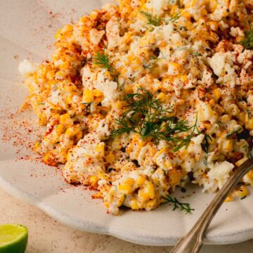 Corn salad on a white plate topped with fresh dill.