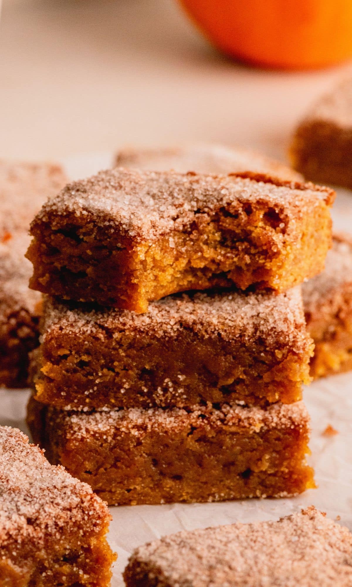 Pumpkin blondies with a cinnamon sugar top cut into squares and stacked in group of three.