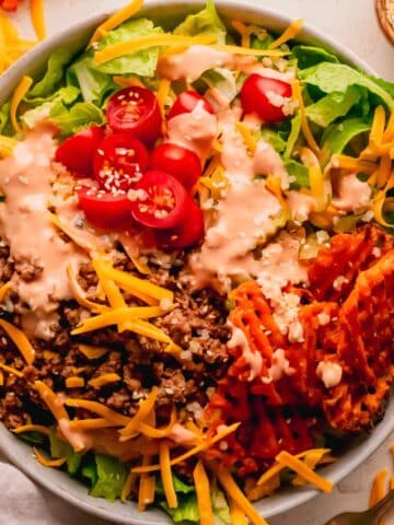 Cheeseburger salad in a white bowl.