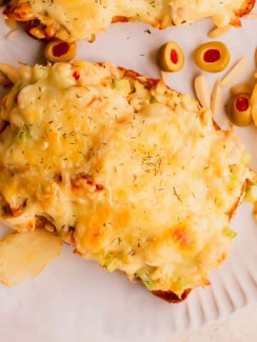 An open face tuna sandwich on a white plate.