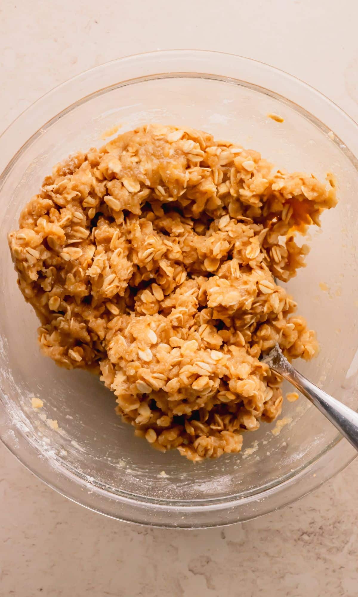 Oat mixture in a glass bowl with a spoon.
