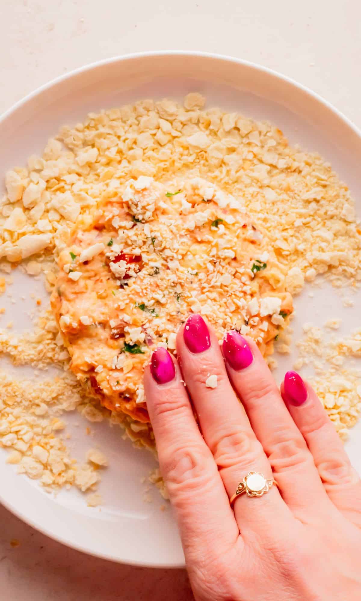 Patting cracker crumbs onto salmon cake.