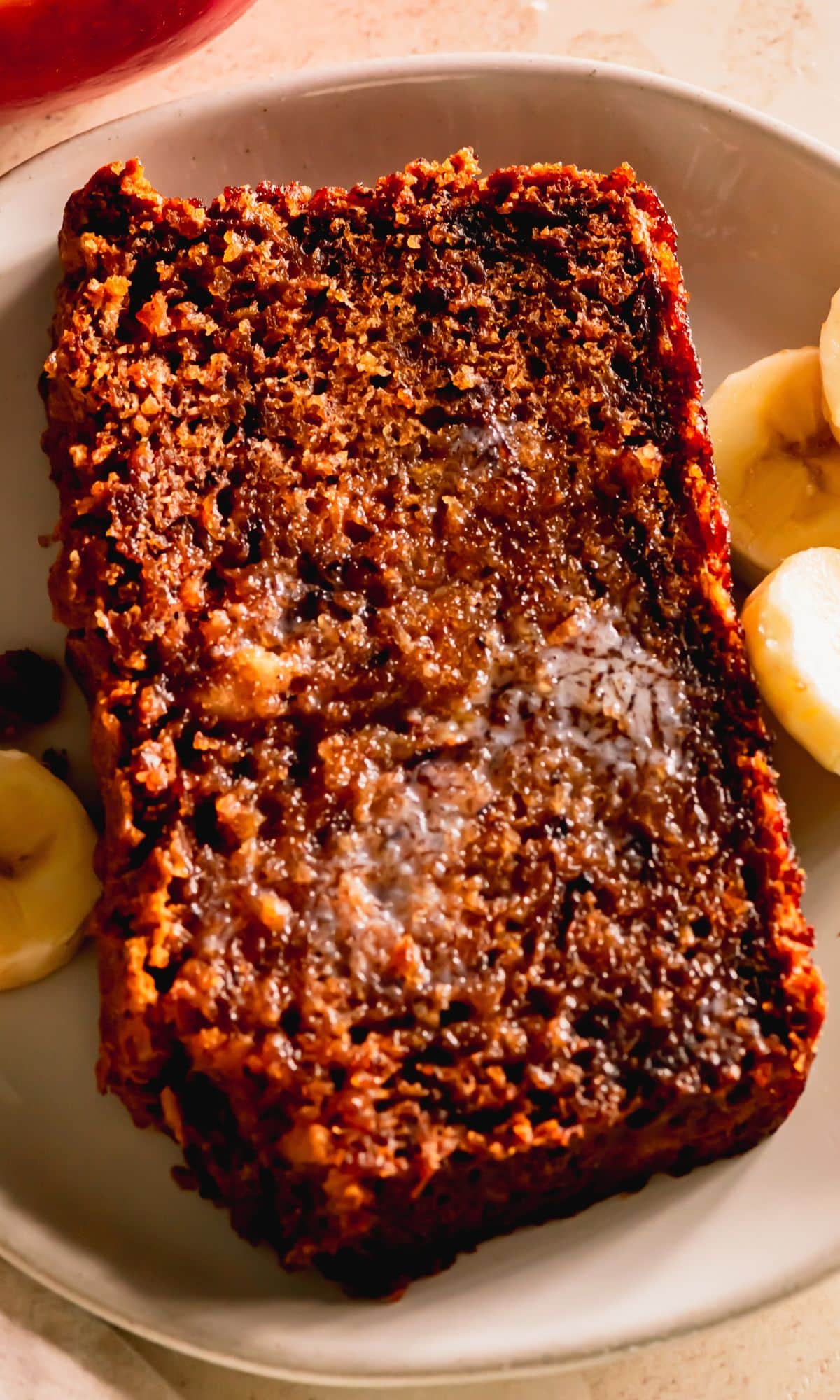 A slice of apple banana bread with melting butter spread on top.