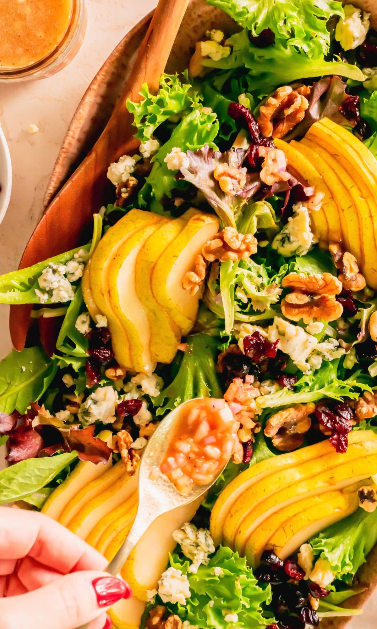Adding walnut vinaigrette to the top of pear blue cheese salad.