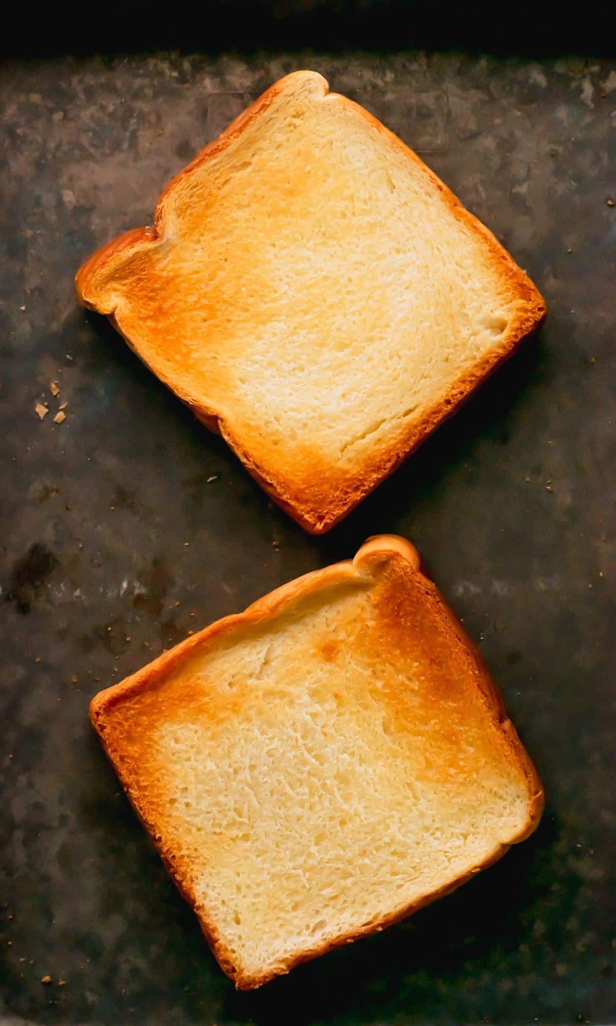 Two toasted pieces of Texas toast on a baking sheet.