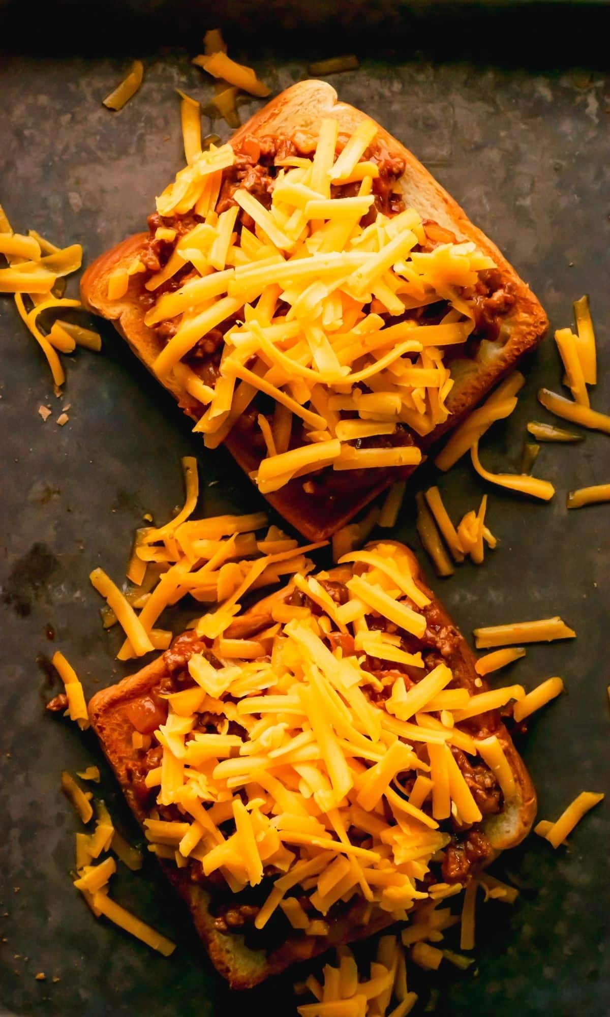 Two open-faced sloppy joes on a baking sheet before baking.