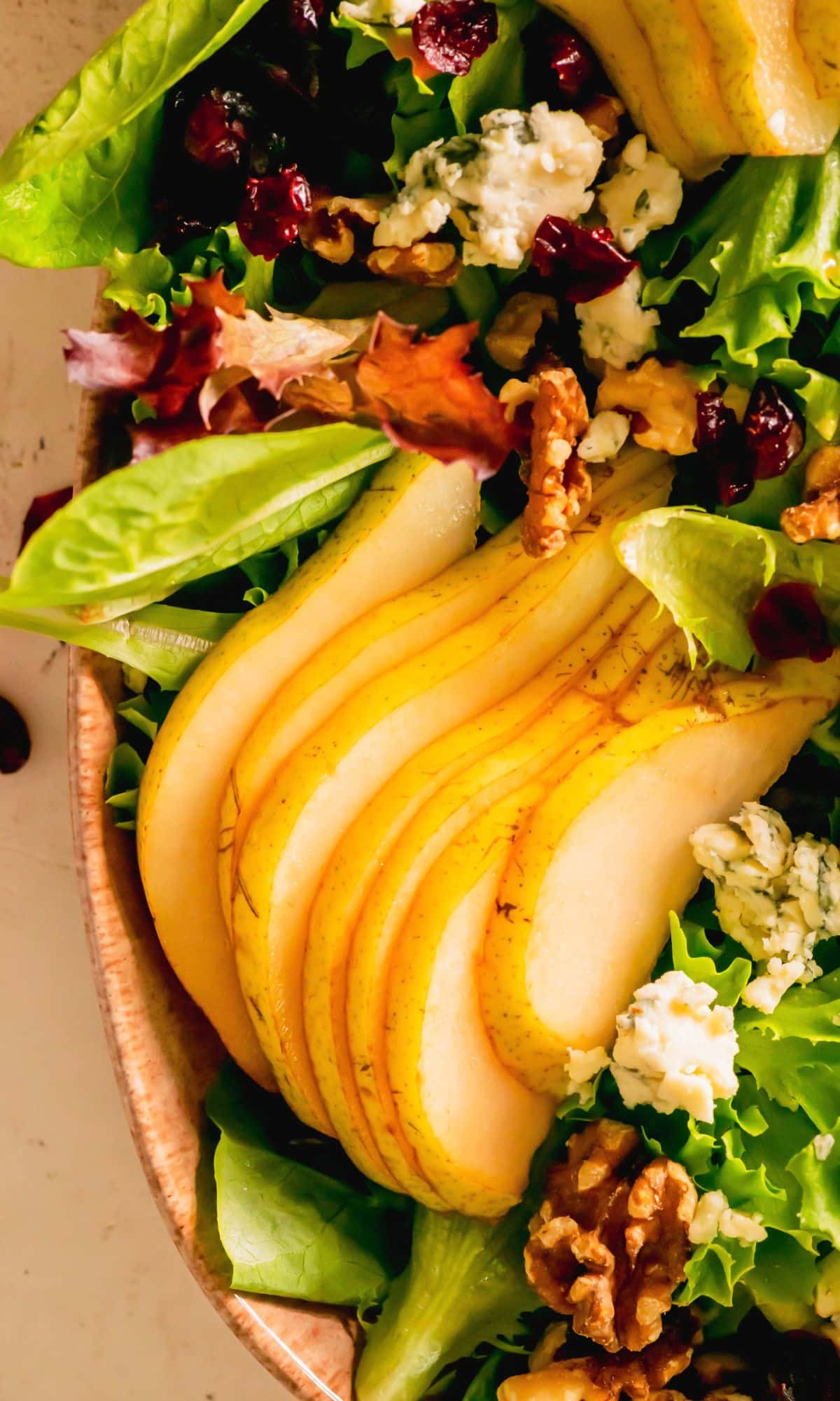Closer view of sliced pears and blue cheese on mixed greens.