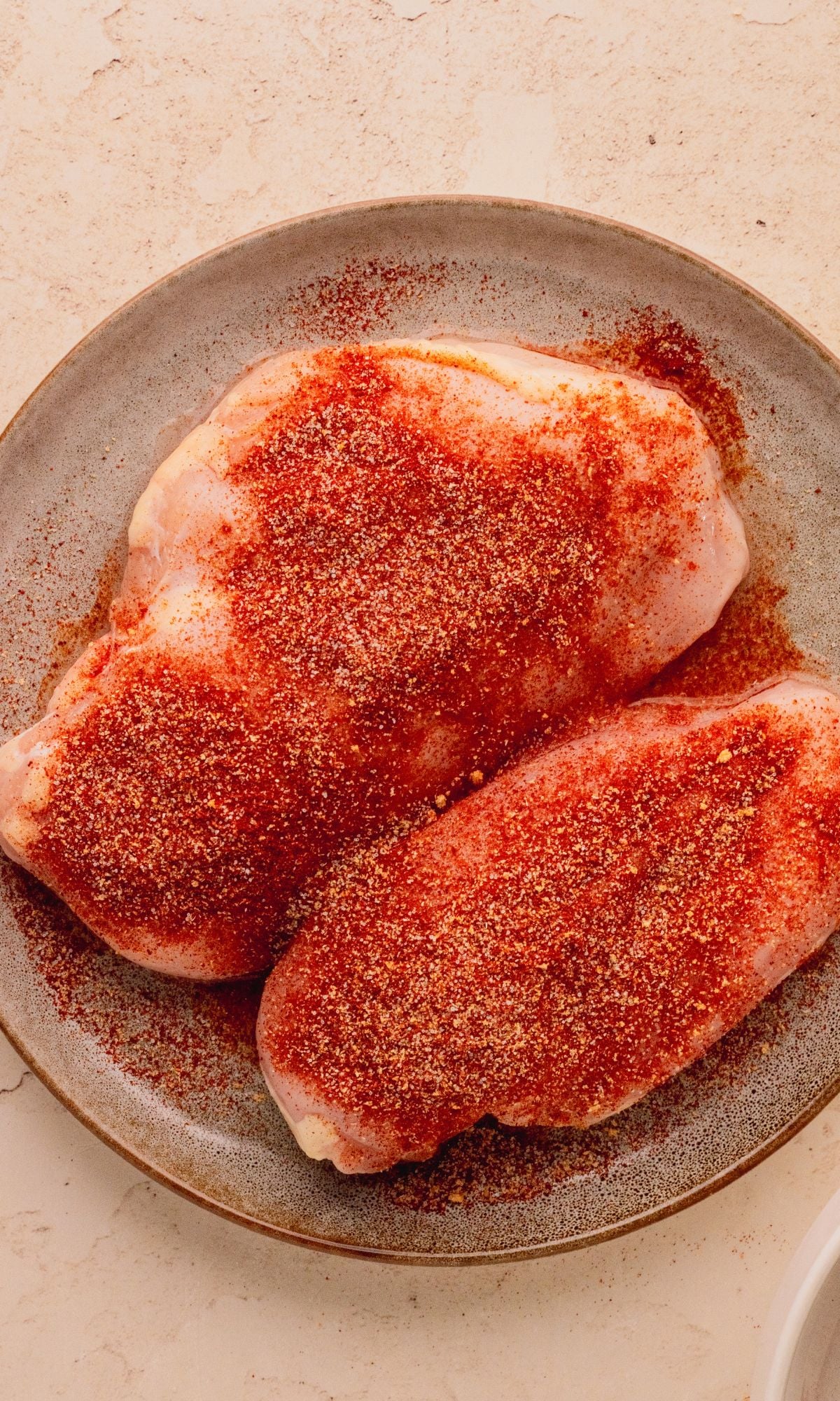 Seasoned chicken breasts on a plate.