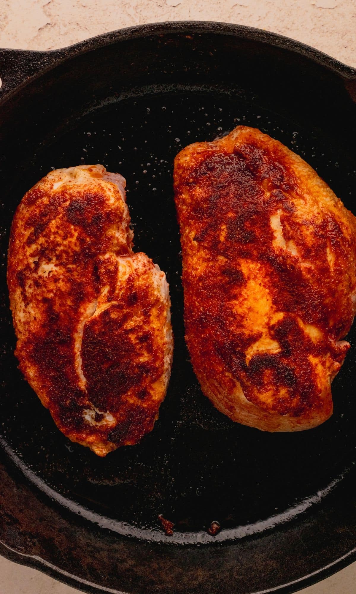 Cooked seasoned chicken breasts in a cast iron skillet.