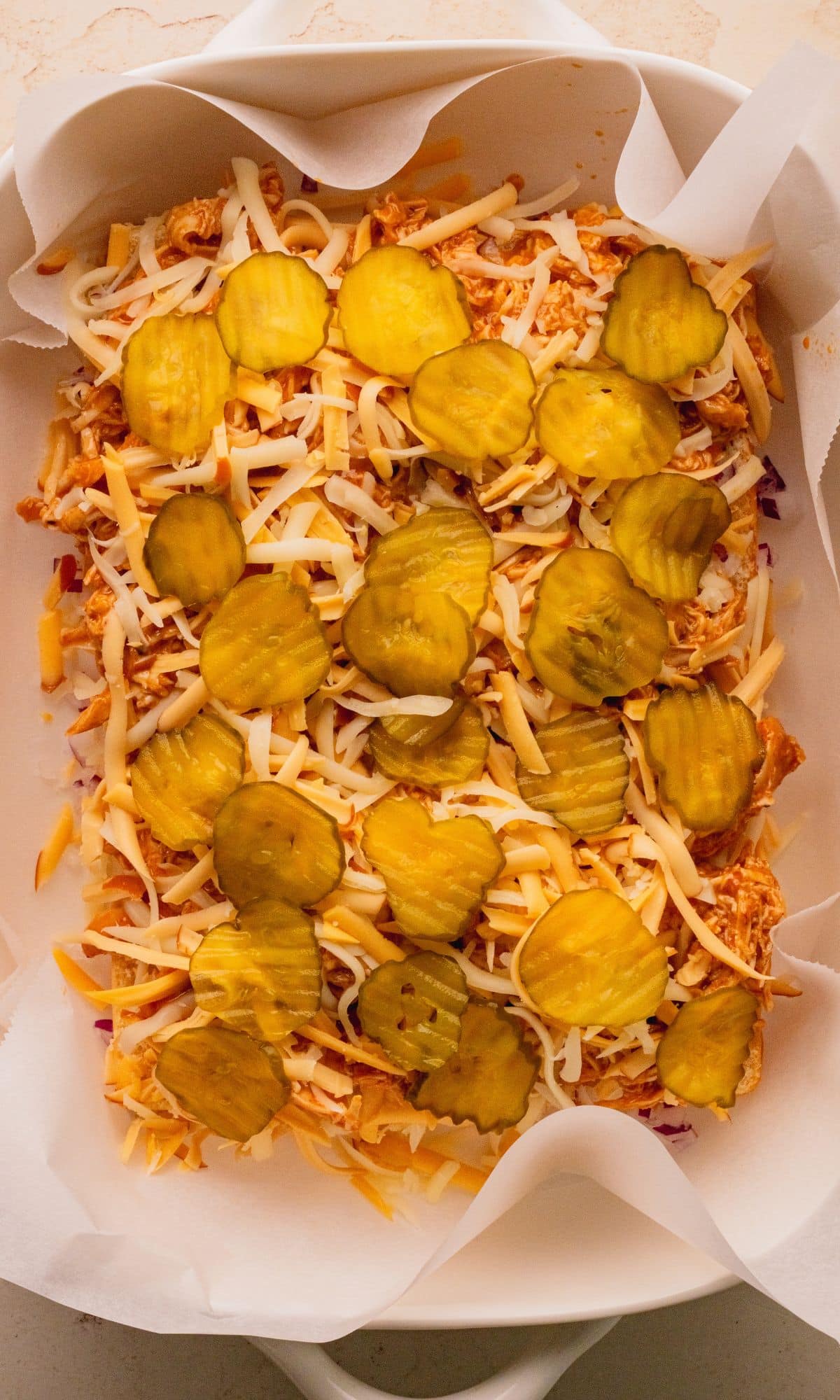 Buffalow chicken sliders assembled without the top bun in a baking dish.